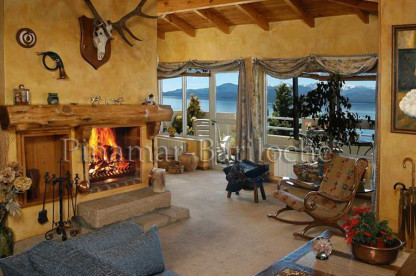 Departamento en alquiler en Bariloche con costa de lago. Capacidad 6 personas. Ambiente principal con estufa hogar encendida y ventanales al Bariloche