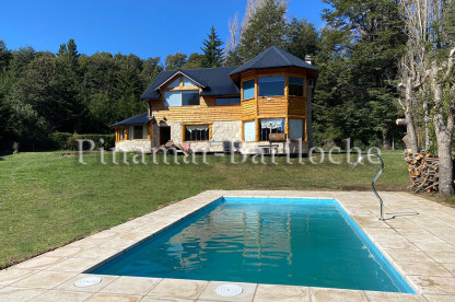 Casa en alquiler en Bariloche con pileta climatizada, gran parque cercado. Vista desde el parque a pileta y casa de montaña en Bariloche