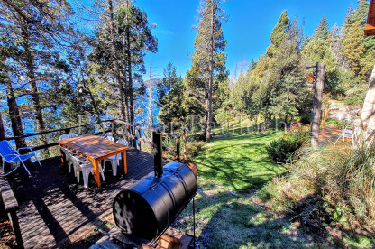Cabaña con costa de lago en Bariloche, exterior con deck. Capacidad 6 personas. Vista exterior, parque y deck con chulengo en Bariloche