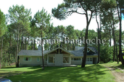 Fachada de casa en alquiler en Cariló, rodeada de bosque y amplio jardín, ideal para vacaciones en familia. Gran parque y frente de la propiedad en alquiler en Cariló.