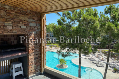 Balcón con parrilla y vista a la piscina en Pinamar
