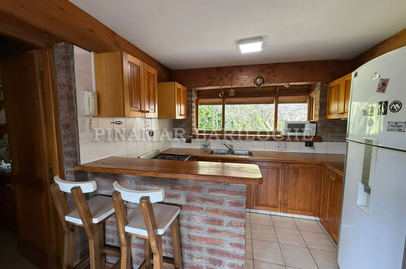 Cocina completa con barra y butacas.