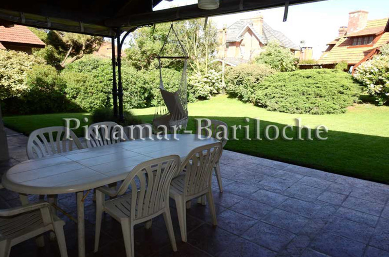 Galería techada con mesa exterior y parrilla.